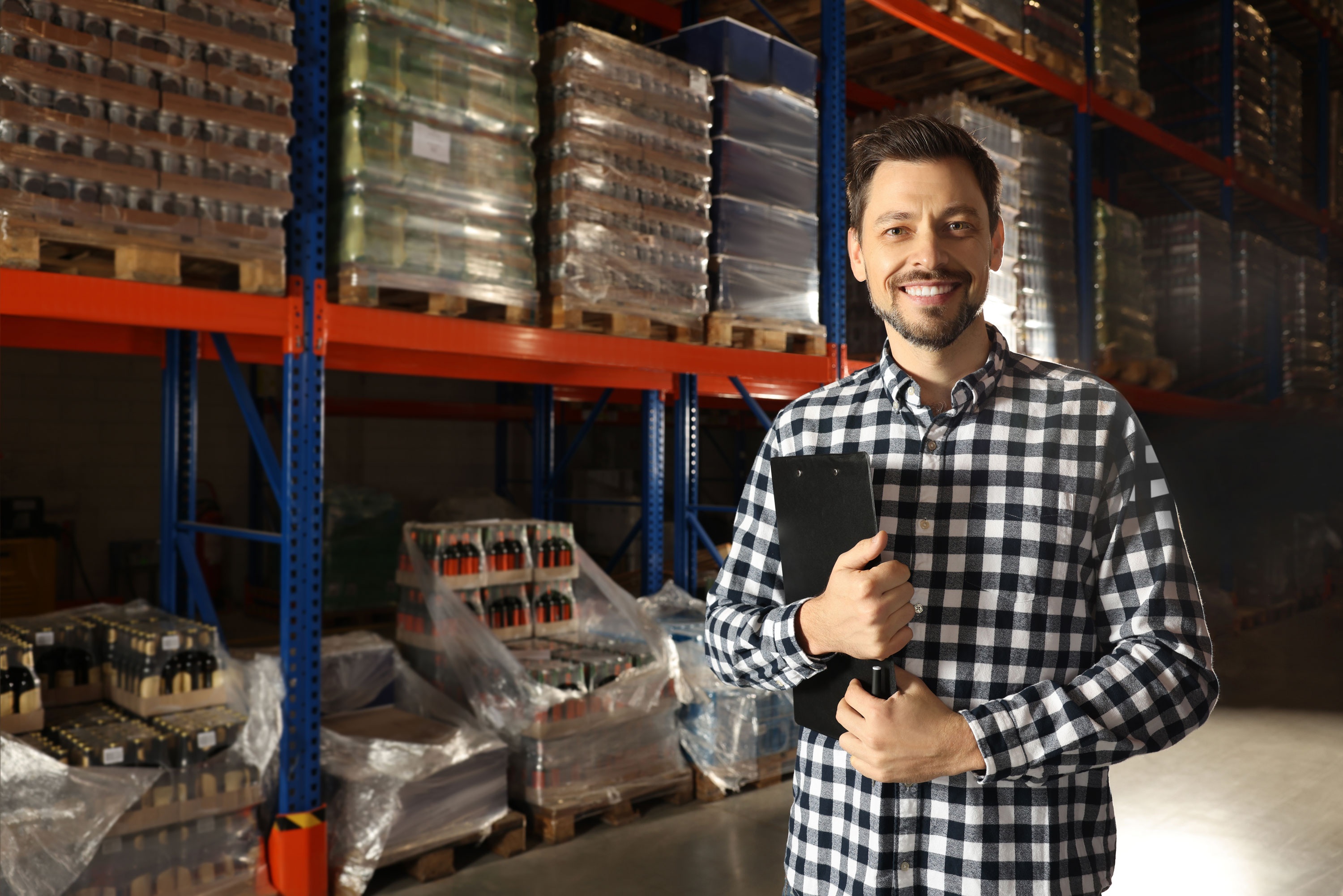 Male employee in distributor warehouse holding a clipboard